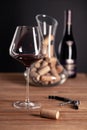 Crystal red wine glass, bottle, corkscrew, opener, sommelier knife, transparent decanter, corks on wooden table. Closeup Royalty Free Stock Photo