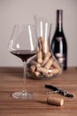 Crystal red wine glass, bottle, corkscrew, opener, sommelier knife, transparent decanter, corks on wooden table. Closeup, vertical Royalty Free Stock Photo