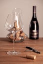 Crystal red wine glass, bottle, corkscrew, opener, sommelier knife, transparent decanter, corks on wooden table. Closeup Royalty Free Stock Photo
