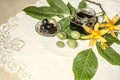 Glass jar with nut jam near the green walnuts with leaves and orange lilies