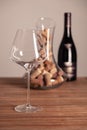 Crystal shiny glass, bottle of red wine, transparent decanter filled with corks on wooden table. Closeup, vertical Royalty Free Stock Photo