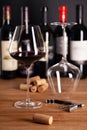 Crystal shiny glass of red wine, bottles, corkscrew, opener, sommelier knife, transparent decanter, corks on wooden Royalty Free Stock Photo