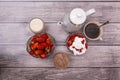 Crystal vases ripe strawberries, glasses cocktail, cup of coffee and teapot stand on wooden table. View from above. Royalty Free Stock Photo