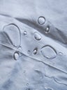 Crystal water droplets shining in light on white drapery with folds Royalty Free Stock Photo