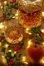 Crystal whisky decanter and a glass of whisky with christmas lights and holly berries