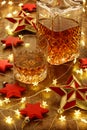 Crystal whisky decanter and a glass of whisky with christmas lights and red stars decorations