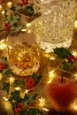 Crystal whisky ice bucket and a glass of whisky with christmas lights and holly berries