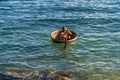 Vietnamese fisherman in a traditional round woven bamboo boat rowing to makeshift living rafts on open sea of Cu Lao Cham island
