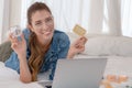 Cuacasian woman laying on bed holding shopping card and a case of cosmetic on hand with laptop computer inconcept of shopping Royalty Free Stock Photo