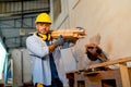 Cuacasian wood worker or carpenter hold and carry bundle of timber and stand near electrical saw during work in factory workplace