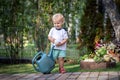 Cuate adorable caucasian blond little toddler boy in watering flowerbed flower pot with green plastic can outdoors. Fun baby boy Royalty Free Stock Photo