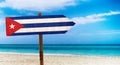 Cuba flag on wooden table sign on beach background. It is summer sign of Cuba