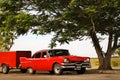 Cuba, Havana - January 16, 2019: Old American red car in the old city of Havana against the tropical tree