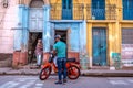 Cuba, Havana - Mar 9th 2018 - Local people of Havana parking a old, very simple motorcycle in front of a old, bit damage house in