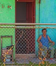 Cuba, Havana, October, 2019: Old Cuban woman on chair sitting in street near door of hose. Caribbean communism village. daily life