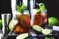 Cuba libre alcohol cocktail with golden rum, lemon juice, cola, lime and ice, dark bar counter background, bar tools, place for Royalty Free Stock Photo