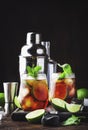 Cuba libre alcohol cocktail with golden rum, lemon juice, cola, lime and ice, dark bar counter background, bar tools, place for Royalty Free Stock Photo