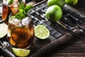 Cuba libre alcohol cocktail with golden rum, lemon juice, cola, lime and ice, dark bar counter background, bar tools, place for Royalty Free Stock Photo