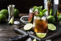 Cuba libre alcohol cocktail with golden rum, lemon juice, cola, lime and ice, dark bar counter background, bar tools, place for Royalty Free Stock Photo