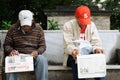 Cuba: Two older men sitting on a bank in a park in Havana reading the newspapers Royalty Free Stock Photo