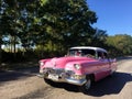 Cuban classic car moving on a contry road. Pink Cadillac in Cuba. Royalty Free Stock Photo