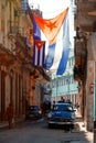 Cuban flags, antique cars, people and aged buildings in Old Havana Royalty Free Stock Photo