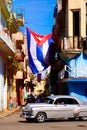 Cuban flags, antique cars, people and aged buildings in Old Havana Royalty Free Stock Photo