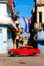 Cuban flags, antique cars, people and aged buildings in Old Havana Royalty Free Stock Photo