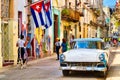 Cuban flags, classic car and colorful decaying buildings in Old Havana