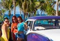 Cuban Latinas posing on the american blue white Ford Fairlane vintage car on the beach in