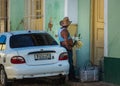 A Cuban man with a flower and car in street of Caribbean colorful colonial town, Trinidad, communism Cuba, America