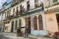 Cuban man holding unto old gate next to his vintage tricycle