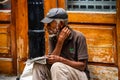 Cuban old man, reading morning newspaper while sitting on the street, everyday lifestyle or way of life in the Old Town of Havana