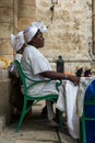 Cuban woman in traditional white clothes selling dolls to tourists