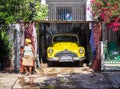 Cuban women with yellow head scarf next to a matching car