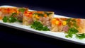 Cubes of aspic with boiled meat, paprika, carrots and maize corn, served with parsley on black background