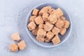 Cubes of brown sugar or cane sugar in bowl and on gray background, horizontal, top view Royalty Free Stock Photo