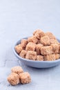 Cubes of brown sugar or cane sugar in bowl and on gray background, vertical, copy space Royalty Free Stock Photo
