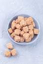 Cubes of brown sugar or cane sugar in bowl and on gray background, vertical, top view Royalty Free Stock Photo