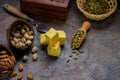 Cubes of dessert patisa, cardamom grains in wooden scoop, pistachios and almond on concrete kitchen worktop