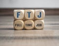 Cubes or dice with acronym FTJ for Full Time Job on wooden background Royalty Free Stock Photo