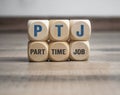 Cubes or dice with acronym PTJ for Part Time Job on wooden background