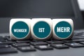 Cubes, dice or blocks on laptop keyboard with the german word for less is more - weniger ist mehr Royalty Free Stock Photo