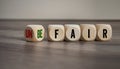 Cubes and dice with fair and unfair on wooden background Royalty Free Stock Photo