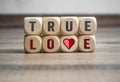 Cubes and dice with message true love with heart icon on wooden background Royalty Free Stock Photo