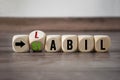 Cubes and dice showing the german words stable and unstable - stabil und unstabil on wooden background