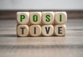 Cubes and dice showing the word positive in green colour on wooden background