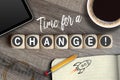 Cubes and dice on a wooden background with sketchbook, tablet and coffee with message time for a change