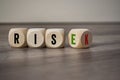 Cubes and dice with the words rise and risk on wooden background