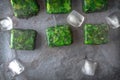 Cubes of frozen spinach with ice cubes on the stone table horizontal Royalty Free Stock Photo